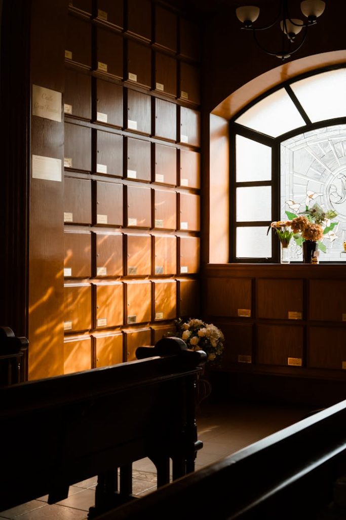Peaceful memorial room with sunlight streaming through window illuminating shelves and flowers.